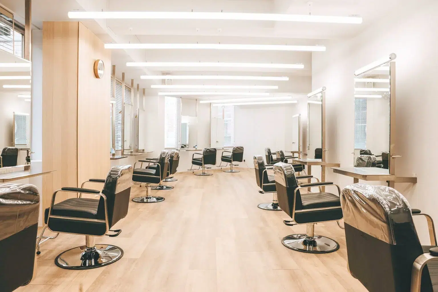 MUUM HAIR SALON 室內，木質地板、黑色造型椅與兩側鏡台