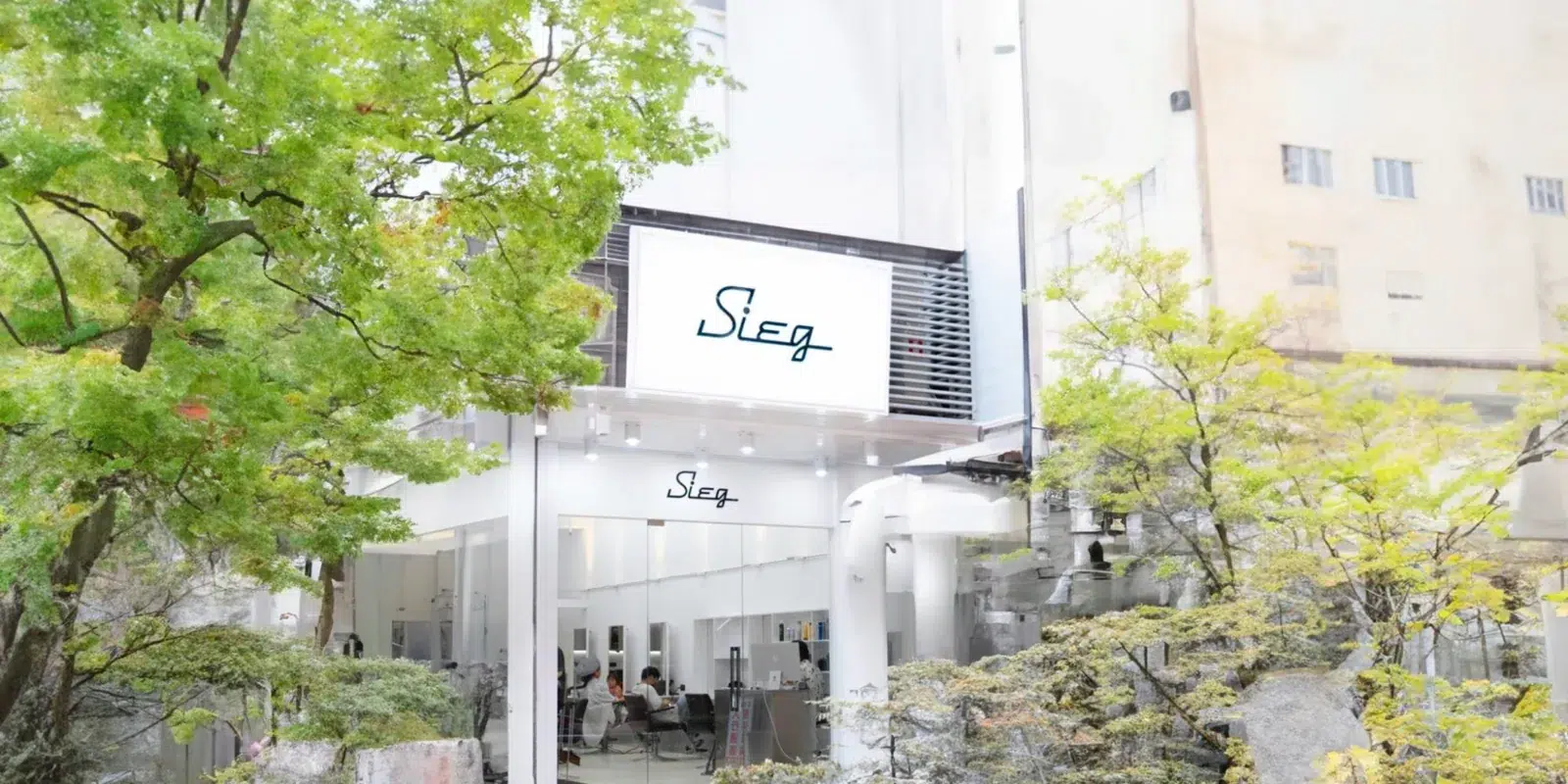 SIEG 中壢威尼斯店外觀，綠樹旁的白色店面與 SIEG 招牌